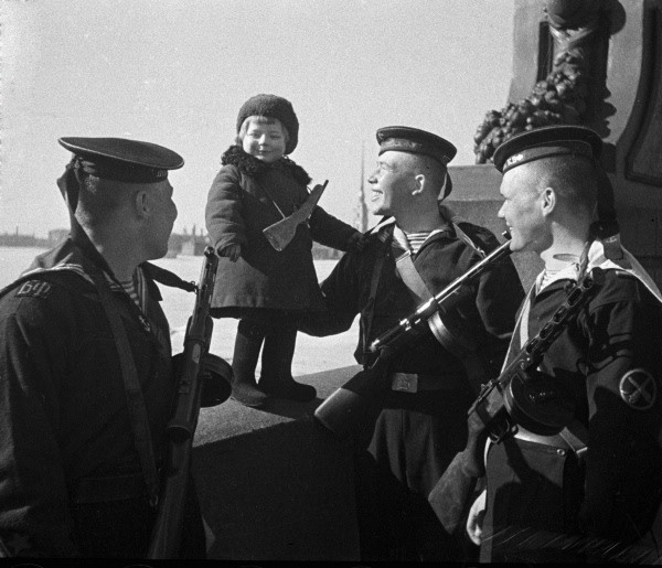 Моряки Балтийского флота с маленькой девочкой Люсей, родители которой умерли в блокаду. Ленинград, 1 мая 1943 г.