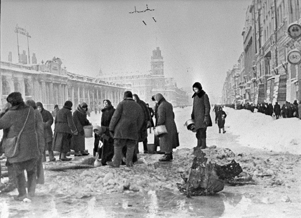 Жители блокадного Ленинграда набирают воду, появившуюся после артобстрела в пробоинах в асфальте на Невском проспекте, фото Б. П. Кудоярова, декабрь 1941